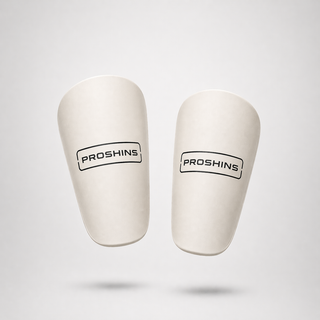 Pair of white shin guards with 'ProShins' branding on a light gray background